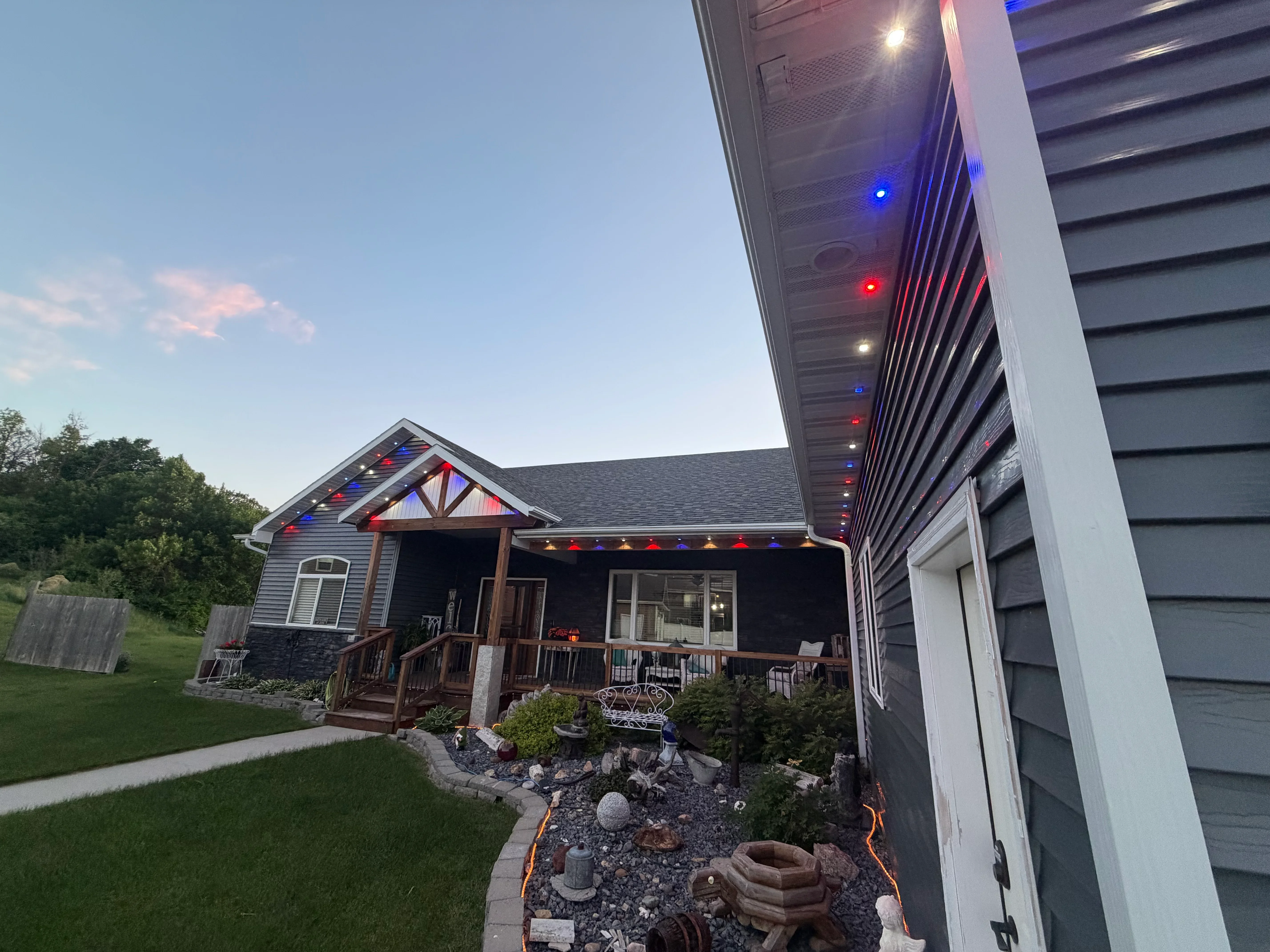 Red, white, and blue LED lights installed on residential home roofline and soffit with landscape lighting