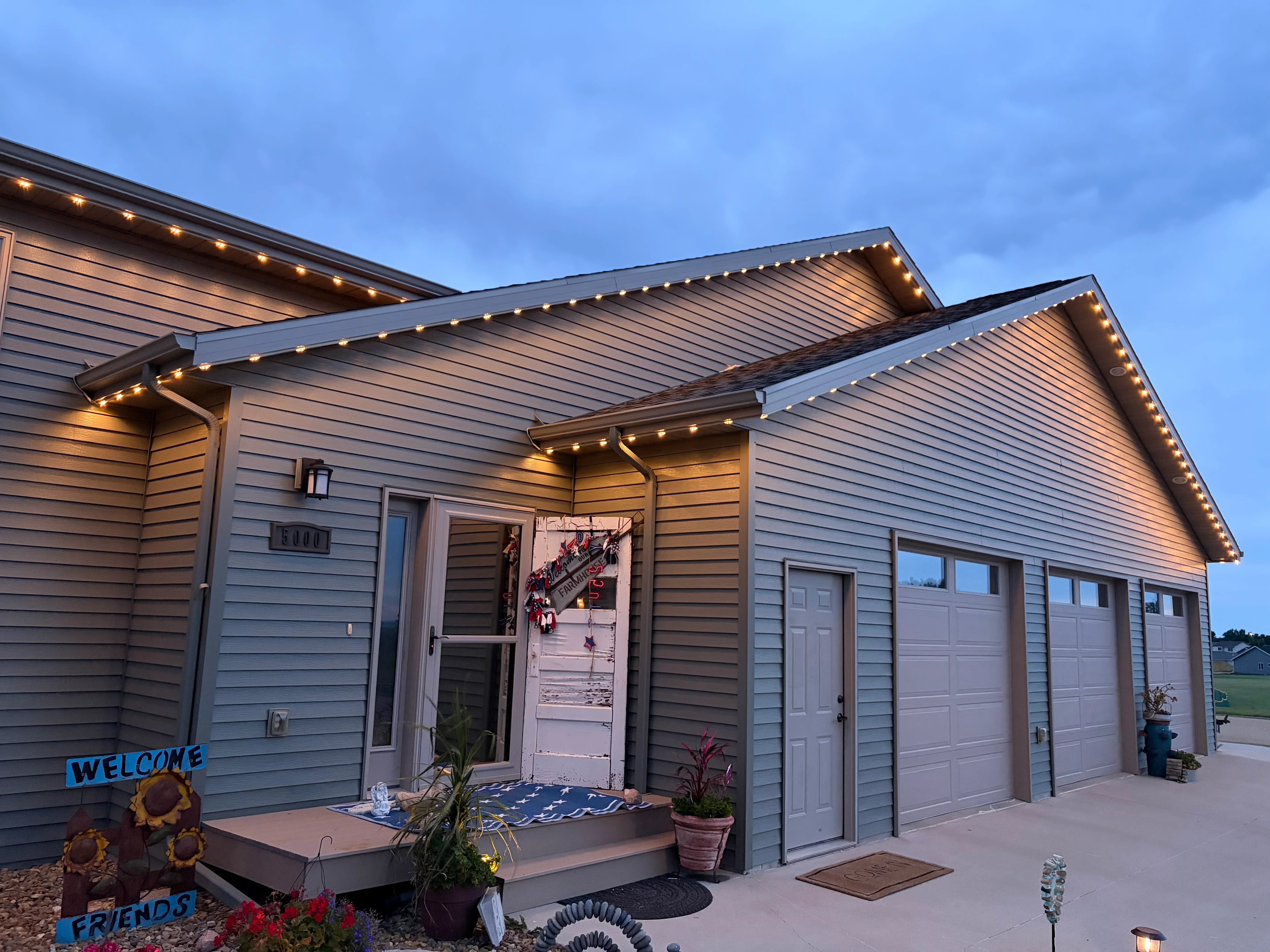 LED string lights installed along soffit, roofline, and pergola of residential home exterior at dusk