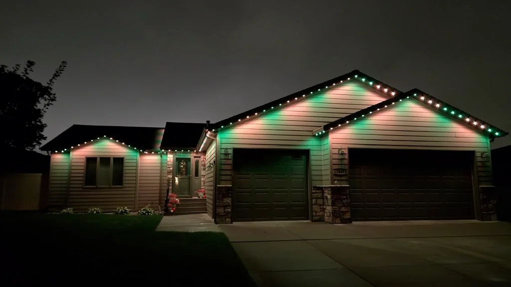 LED soffit and roofline lighting with green and warm white accent lights on residential home exterior